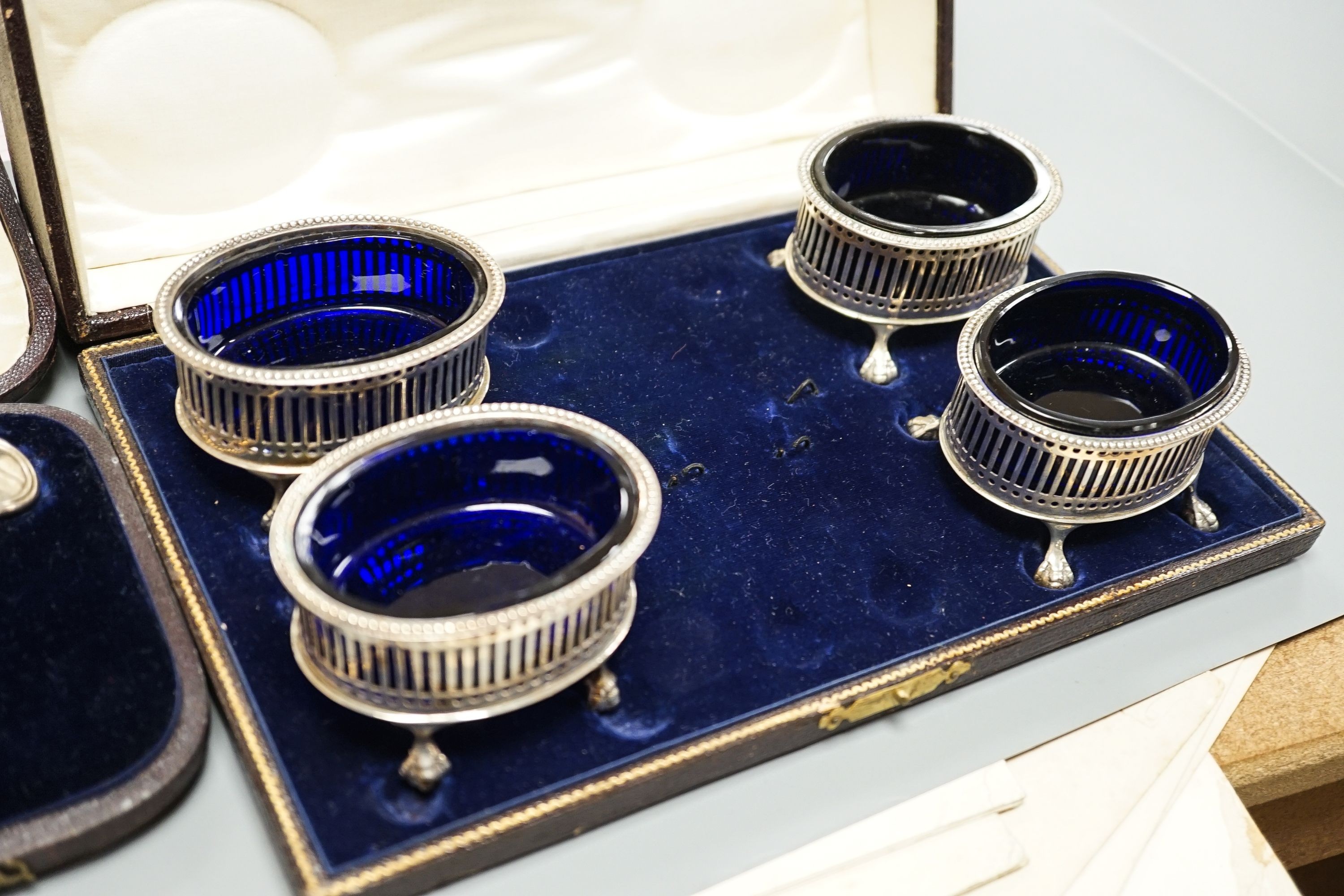 A cased pair of Victorian silver fish servers, London, 1856, together with a cased set of four George V pierced silver oval salts with cobalt blue glass liners (no spoons).
